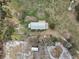 Areal view of home with metal roof, outbuildings, vehicles, and open land surrounded by mature trees at 2040 Underwood Ln, Zephyrhills, FL 33540