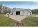 White barn with gray accents, open doors, and brick paver patio at 2040 Underwood Ln, Zephyrhills, FL 33540