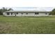 Exterior view of the home showcasing its white facade, metal roof, expansive lawn, and multiple windows and doors at 2040 Underwood Ln, Zephyrhills, FL 33540
