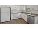All-white kitchen featuring modern appliances, granite countertops, ample cabinet space, wood floors, and a stainless steel dishwasher at 2040 Underwood Ln, Zephyrhills, FL 33540
