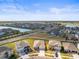 Aerial view of a community showcasing houses, streets, landscaping, and a nearby pond at 2839 Gumbo Limbo Dr, Wimauma, FL 33598