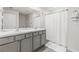 Bathroom featuring double vanity with marble countertop and grey cabinets and shower with white curtain at 2839 Gumbo Limbo Dr, Wimauma, FL 33598