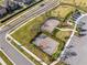 Aerial view of tennis and basketball courts adjacent to a parking lot and well-manicured landscape at 2839 Gumbo Limbo Dr, Wimauma, FL 33598