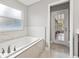 Bright bathroom features a bathtub with white marble tile surround and access to the screened porch at 3038 Longbrooke Way, Clearwater, FL 33760
