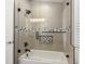 Modern bathroom featuring a shower over tub with gray tile and decorative mosaic accents, and a glass enclosure at 4564 Juniper Dr, Palm Harbor, FL 34685