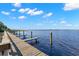 Picturesque view of a wooden dock extending into calm, deep-blue water under a sunny sky at 4564 Juniper Dr, Palm Harbor, FL 34685