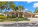 Charming home featuring a tile roof, arched entryway, manicured landscaping, and a spacious three-car garage at 4564 Juniper Dr, Palm Harbor, FL 34685