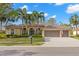 Charming home featuring a tile roof, arched entryway, manicured landscaping, and a spacious three-car garage at 4564 Juniper Dr, Palm Harbor, FL 34685