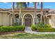 Close-up of the home's arched entryway with double doors, decorative wreath, and manicured landscaping at 4564 Juniper Dr, Palm Harbor, FL 34685