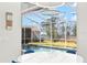 View of a screened-in pool from the dining area, with a blue table and chairs in the foreground at 4564 Juniper Dr, Palm Harbor, FL 34685