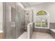 Elegant walk-in shower with gray tiling, a built-in seat, and seamless glass enclosure at 4564 Juniper Dr, Palm Harbor, FL 34685