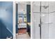 Stylish bathroom showcasing glass-enclosed shower, blue walls, and hexagon tile flooring leading to bedroom at 5010 W Dickens Ave, Tampa, FL 33629