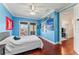 Bright bedroom with hardwood floors, light-blue walls, crown molding, and sunny windows overlooking the balcony at 5010 W Dickens Ave, Tampa, FL 33629