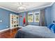 Cozy bedroom features hardwood floors, blue walls, large window, and a shelving unit with storage at 5010 W Dickens Ave, Tampa, FL 33629