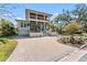 Two-story home featuring a metal roof, front balcony and a paved driveway with attractive landscaping at 5010 W Dickens Ave, Tampa, FL 33629