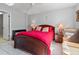 Bright main bedroom features a red bedspread, ceiling fan and natural light at 6428 Thicket Trl, New Port Richey, FL 34653
