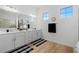 A spacious bathroom featuring double vanity, modern mirrors, two windows, and wood grain tile flooring at 7934 Lakes Edge Ln, Port Charlotte, FL 33981
