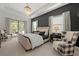 A bedroom featuring a tray ceiling, modern chandelier, and a cozy sitting area with outside access at 7934 Lakes Edge Ln, Port Charlotte, FL 33981