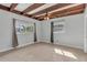 Sunlit bedroom featuring exposed beam ceiling, two windows, and neutral carpeting at 8040 Owl Rd, Seminole, FL 33777