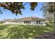 Expansive backyard featuring lush green grass, mature trees, and a screened-in patio at 988 Villeroy Greens Dr, Sun City Center, FL 33573