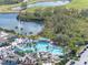 Aerial view of a large community pool area with many people, palm trees, and golf carts at 988 Villeroy Greens Dr, Sun City Center, FL 33573