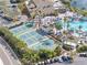Aerial view of community pool with tennis courts, palm trees, and plenty of seating for residents at 988 Villeroy Greens Dr, Sun City Center, FL 33573