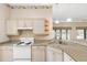 Functional kitchen featuring a white oven and cabinets, granite countertops, and an eat-in breakfast bar at 988 Villeroy Greens Dr, Sun City Center, FL 33573