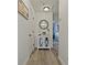 Bright hallway featuring wood look tile and a decorative cabinet with glass doors and round mirror at 10136 Grand Oak Cir, Madeira Beach, FL 33708