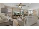 Open-concept living room with neutral colors, tile flooring, large TV, and natural lighting at 10136 Grand Oak Cir, Madeira Beach, FL 33708