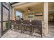 Outdoor kitchen features stone bar, grill, beverage cooler and mounted tv at 10136 Grand Oak Cir, Madeira Beach, FL 33708