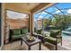 Comfortable seating on patio with view of pool and lush landscaping at 10136 Grand Oak Cir, Madeira Beach, FL 33708