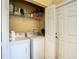 Efficient laundry room with washer, dryer, shelving and a folding door at 16112 Amethyst Key Dr, Wimauma, FL 33598