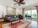 Spacious living room featuring hardwood floors, a ceiling fan, and sliding glass doors to the patio at 16112 Amethyst Key Dr, Wimauma, FL 33598