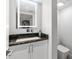Modern half bath features a black marble countertop, lighted mirror, and sleek fixtures at 1660 Gulf Blvd # Ph2, Clearwater Beach, FL 33767