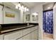 A clean bathroom with a granite countertop, double vanity, and a separate shower with a patterned curtain at 200 Country Club Dr # 503, Largo, FL 33771