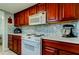 A well-equipped kitchen features wood cabinets, white appliances, and a stylish tile backsplash at 200 Country Club Dr # 503, Largo, FL 33771