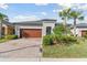 Charming single-story home with well-manicured landscaping, brick driveway, and a beautiful dark wood garage door at 31675 Cannon Rush Dr, San Antonio, FL 33576