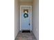 Stylish front door with a wreath, glass pane, 'hello' mat and classic hardware enhancing curb appeal at 31675 Cannon Rush Dr, San Antonio, FL 33576