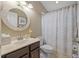 Inviting bathroom with a patterned shower curtain, round mirror, and neutral-colored walls at 7634 Nottinghill Sky Dr, Apollo Beach, FL 33572