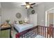 Bedroom featuring soft gray walls, a ceiling fan, comfortable queen bed, and a crib at 7634 Nottinghill Sky Dr, Apollo Beach, FL 33572