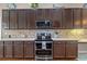 Close up of kitchen with dark cabinets, stainless steel appliances, and decorative backsplash at 7634 Nottinghill Sky Dr, Apollo Beach, FL 33572