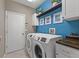Bright laundry room with a blue accent wall and open shelving at 7634 Nottinghill Sky Dr, Apollo Beach, FL 33572