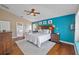 Cozy main bedroom with a decorative blue accent wall, ceiling fan, and wood floors at 7634 Nottinghill Sky Dr, Apollo Beach, FL 33572