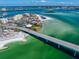 Expansive aerial view showcasing waterfront condos, a sandy beach, and bridge over clear, turquoise water with a city skyline in the distance at 825 S Gulfview Blvd # 208, Clearwater Beach, FL 33767