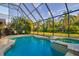 Screened in pool with spa, overlooking a fenced in backyard with tropical landscape at 10534 Bermuda Isle Dr, Tampa, FL 33647