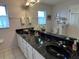 Bathroom with double sinks, black countertops, and white cabinetry at 11138 Brooklawn Dr, Hudson, FL 34667