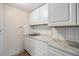 Efficient kitchenette featuring white cabinets, a sink, marble countertops and tile backsplash at 1157 Brook Rd, Clearwater, FL 33755