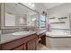 Full bathroom featuring granite counters, vanity, large mirror, soaking tub, and decorative shelves at 13711 Moonstone Canyon Dr, Riverview, FL 33579