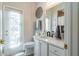 Clean bathroom with white vanity, modern black faucet, a large mirror, and bright natural light through door window at 16331 Burniston Dr, Tampa, FL 33647