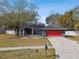 Charming single-story home boasts a red garage door and inviting entrance, complemented by a well-maintained front yard and lush trees at 16508 Round Oak Dr, Tampa, FL 33618